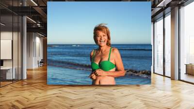 Happy senior latin woman smiling on camera during summer vacation on the beach Wall mural