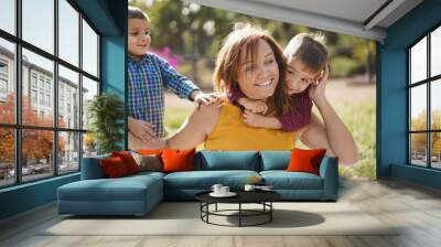 Latin woman smiling while having a playful time with twin sons in nature outdoor - Mother and little children Wall mural