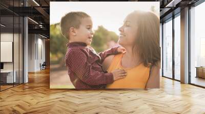 Loving mother holding her son in her arms at city park - Family love concept Wall mural