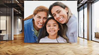 Portrait of happy latin multigenerational family smiling on camera - Grandmother, mother and child having fun together outdoor Wall mural