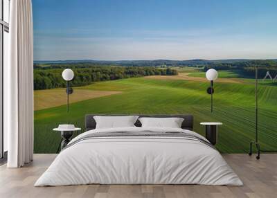 Scenic aerial view of rolling green hills and farmlands under a clear blue sky Wall mural