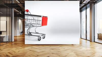 Empty shopping cart with red handle on side position provides copy space for text. background concept isolated white Wall mural