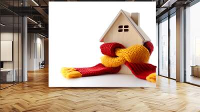 Wooden statuette of a house wrapped in yellow and red knitted scarves on side position provides copy space for text. background concept isolated white Wall mural