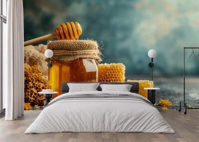 A jar of golden honey with honeycomb and wooden dipper on a rustic table surrounded by flowers in soft light Wall mural