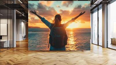 A woman stands on the beach at sunset, embracing the vibrant colors of the sky and ocean Wall mural