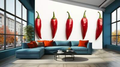 Five vibrant red chili peppers arranged in a straight line on a white background showcasing their glossy texture and pointed tips Wall mural