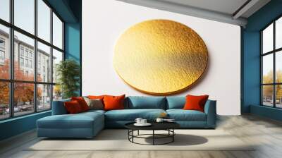 Golden circular piece with a textured surface resting on a white background, reflecting light to showcase its gleaming quality Wall mural