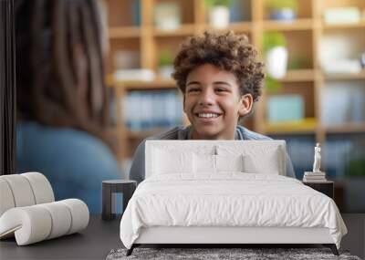 Smiling teenage boy talking with mental health professional while sitting on chair in school office Wall mural