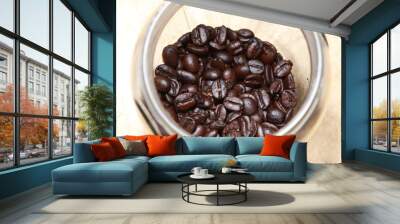 baked and roasted raw coffee beans with glass jar and white plastic scoop isolated on wood background. Wall mural