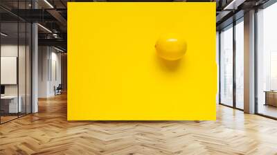 Ripe yellow lemon on a yellow surface, minimalistic background or concept Wall mural