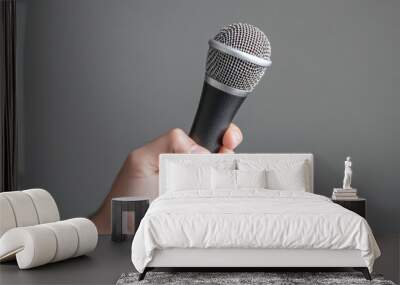 Man’s hand holding a microphone on a blue background. Wall mural