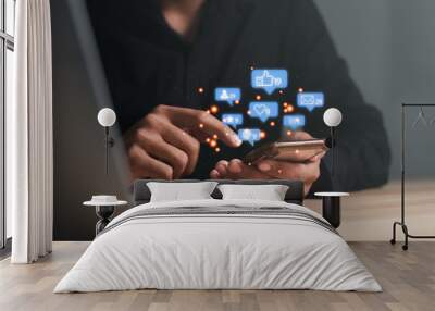 Man using a social media marketing concept on mobile phone with notification icons of like, message, comment and star above smartphone screen. Wall mural