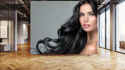 A beautiful woman with long, wavy black hair posing for the camera, showcasing her shiny and healthy looking hair. Wall mural