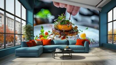 A chef is plating an exquisite dish, showcasing culinary artistry and attention to detail in the kitchen of a high-end restaurant. The plate is beautifully arranged with vibrant ingredients Wall mural