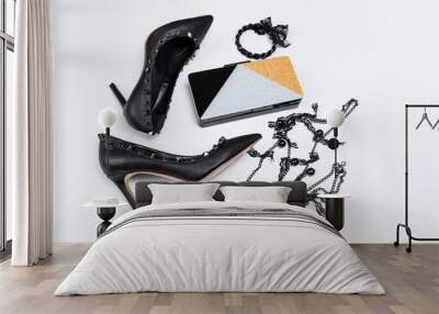 pair of black shoes decorated with metal accents, jewelery with black lace and beads and a tricolor clutch with sparkles on a white background Wall mural