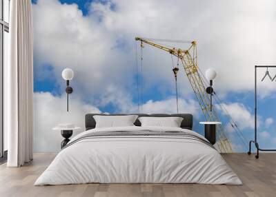 Yellow construction crane on clouds Wall mural