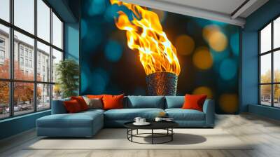 A flaming torch burns brightly against a colorful, blurred background at night Wall mural