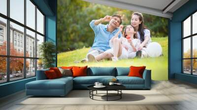 happy asian family playing enjoy funny time together in public park with sunlight sky background. Wall mural