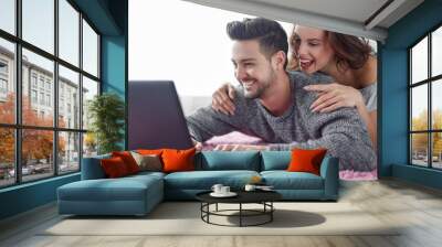 Happy young couple online shopping by laptop at home Wall mural