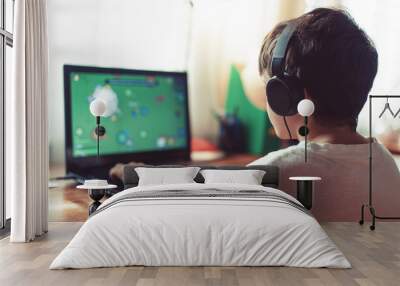 Little dependent gamer boy playing on laptop Wall mural