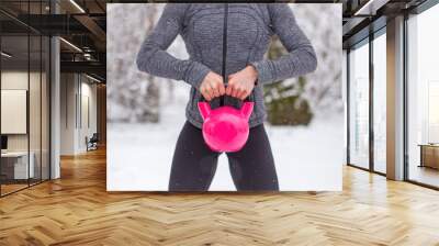 Woman holding pink kettlebells at winter outdoors concept Wall mural