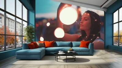 Young brunette woman playing with fairy lights outdoors moody moments Wall mural