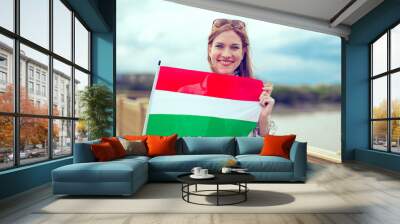 Young redhead woman holding Hungarian flag on bridge Wall mural