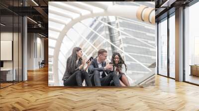 Group of young people use their phones in city talking and smiling Wall mural