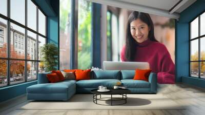 Happy young Asian girl working at a coffee shop with a laptop .Woman happy smiling to camera in cafe day Wall mural