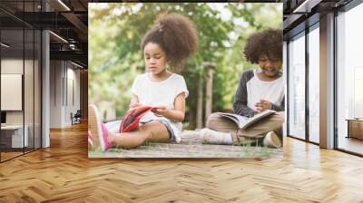 little afro child girl reading book between green spikes meadow garden with friend read education co Wall mural