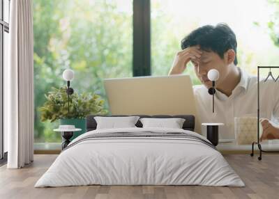 Young Asian man having stressful time working on laptop Wall mural