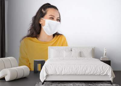 Young happy Asian woman wearing hygienic mask to prevent infection corona virus Air pollution pm2.5 she wearing a yellow sweater shoot in shot isolated on white background Wall mural