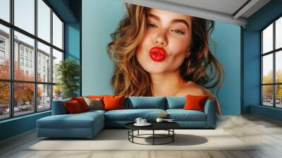 a beautiful young woman with plump red lips sending a kiss into the camera on studio background Wall mural