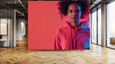 Female fitness model in a magenta hoodie standing confidently, isolated on a magenta background Wall mural