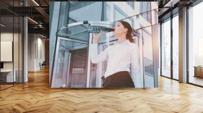 Business lady drinks water from a plastic bottle on the backgrou Wall mural