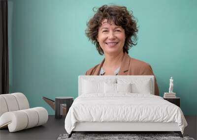 A woman with curly hair smiles warmly while holding a clipboard in a bright workspace Wall mural