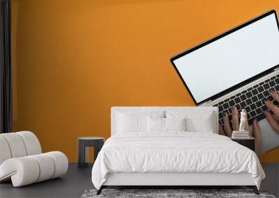 Above view of male designer's hands painted nails using a empty screen of laptop computer on the yellow background. Wall mural