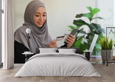 Millennial Arab woman using credit card and smartphone, Shopping Online, Using Credit Card Making Payment, Internet Banking Application and E-Commerce concept. Wall mural