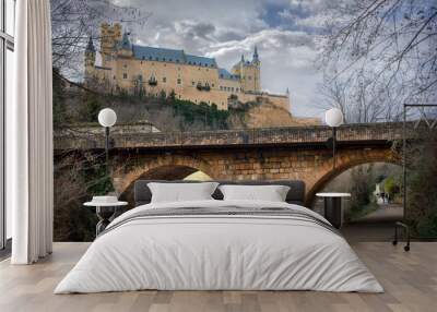 Primer plano de un puente y al fondo tenemos el Alcazar Segovia y a lo lejos dos turistas fotografiando el Alcazar. Wall mural