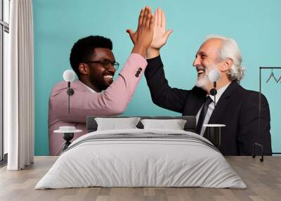 close up mixed race diverse shot of two businessmen, old and young, high fiving isolated on blue background Wall mural