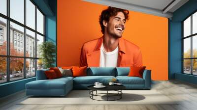 Colourful portrait of a handsome happy man laughing and smiling wearing orange jacket on bright orange background Wall mural