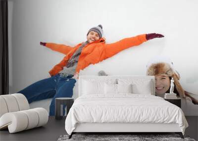 Portrait of happy couple making snow angels Wall mural