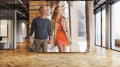 Smiling couple holding hands and walking along corridor in Venice Wall mural