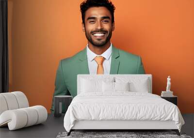 Handsome happy Indian man in green business suit on bright orange colour background, colourful studio portrait Wall mural