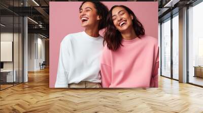 two women laughing in front of pink background Wall mural