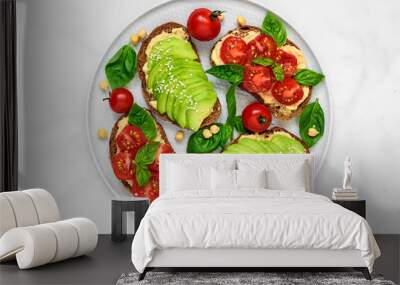 Avocado and tomatoes toasts with hummus, sesame and basil in a plate over white marble background. vegan food Wall mural