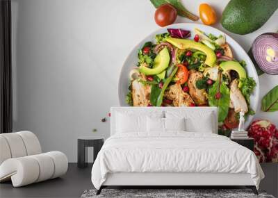 Healthy salad with grilled chicken breast, avocado, pomegranate seeds and tomato on white background. Top view Wall mural