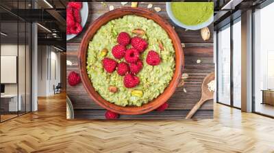 Oatmeal matcha porridge with fresh raspberries and nuts n a bowl for healthy diet breakfast on rustic wooden table Wall mural