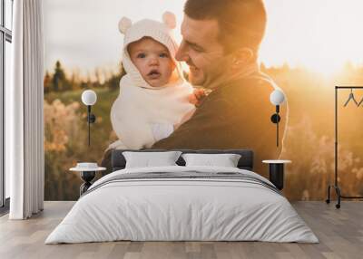 Father holding daughter at sunset Wall mural