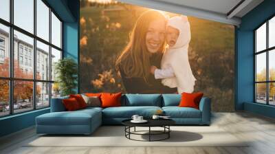 Mother holding daughter at sunset Wall mural